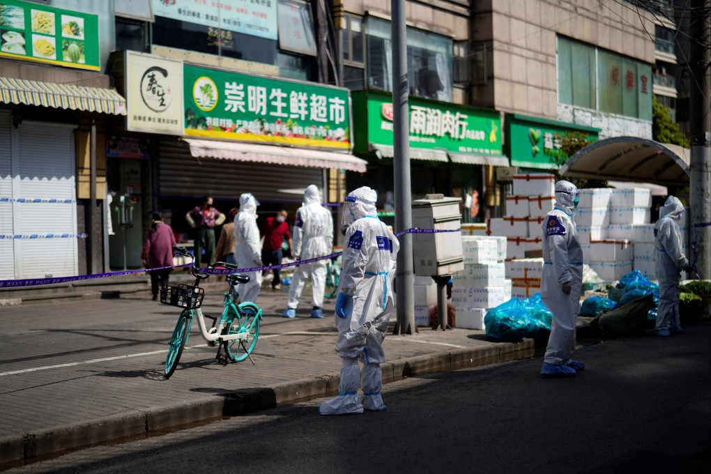 On Tuesday, police and security staff in protective suits stand outside cordoned-off food stores during a coronavirus outbreak in Shanghai. Photo: Reuters