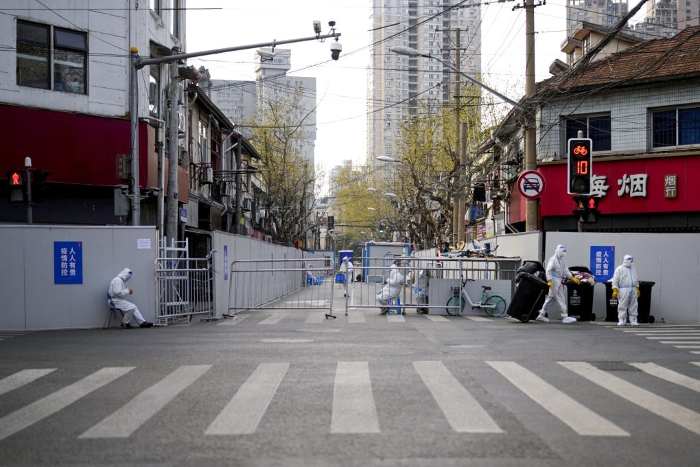 Workers in protective suits keep watch in an area that has been sealed off in Shanghai. Photo: Reuters