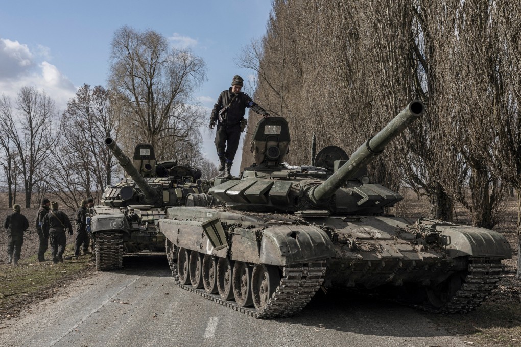 A Ukrainian serviceman stands on top of a Russian tank captured in the village of Lukyanivka outside Kyiv on Sunday. Photo: Reuters