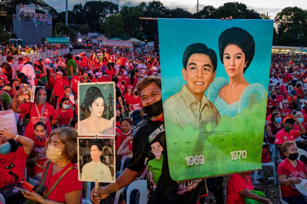 A supporter holds pictures of the late dictator Ferdinand Marcos and his wife Imelda Marcos at a Philippine presidential election campaign rally in Metro Manila. Photo: Getty Images
