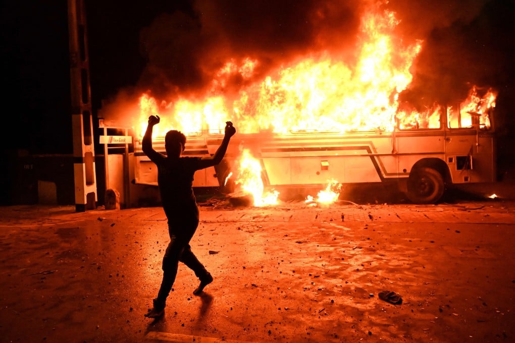 A demonstrator is seen in front of a burning bus as hundreds of people protest outside Sri Lanka’s President Gotabaya Rajapaksa’s home in a Colombo suburb on Thursday. Photo: AFP