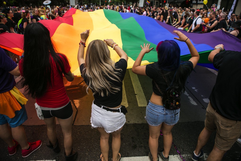 People dance while helping to carry a huge rainbow flag for the annual pride parade in downtown Seattle in June 2015. Photo: TNS
