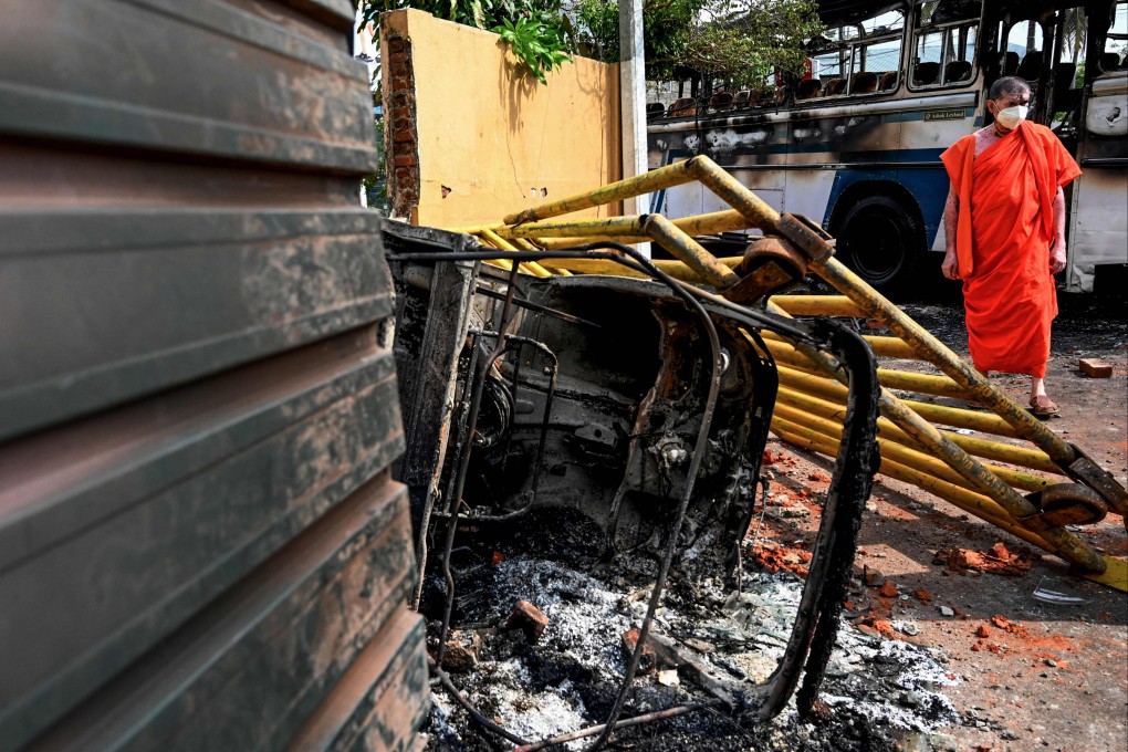 A monk walks past the site near a burned-out bus near Sri Lanka’s President Gotabaya Rajapaksa’s home in Colombo on Friday. Security forces were deployed across the Sri Lankan capital after protesters tried to storm the president’s home in anger at the nation’s worst economic crisis since independence. Photo: AFP