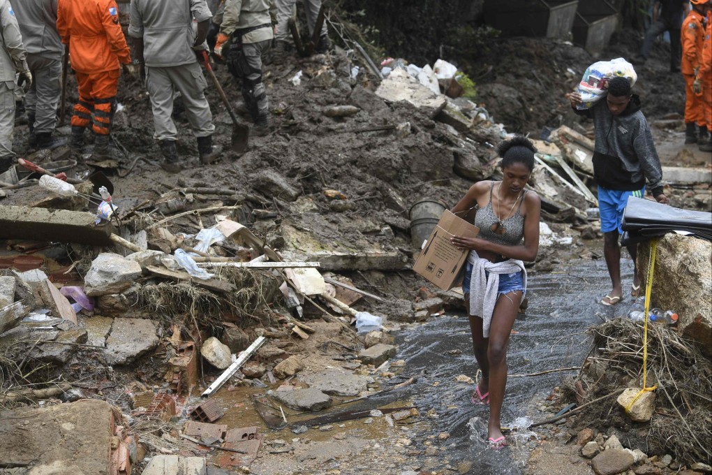 People carry belongings after a giant landslide in Petropolis, Brazil after torrential rains triggered flash floods and landslides. Photo: AFP