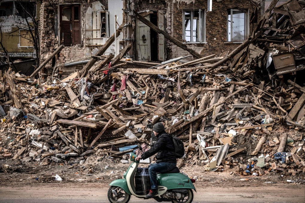 A man rides a scooter past the rubble of a destroyed building in Kharkiv, Ukraine, on Saturday. Photo: AFP