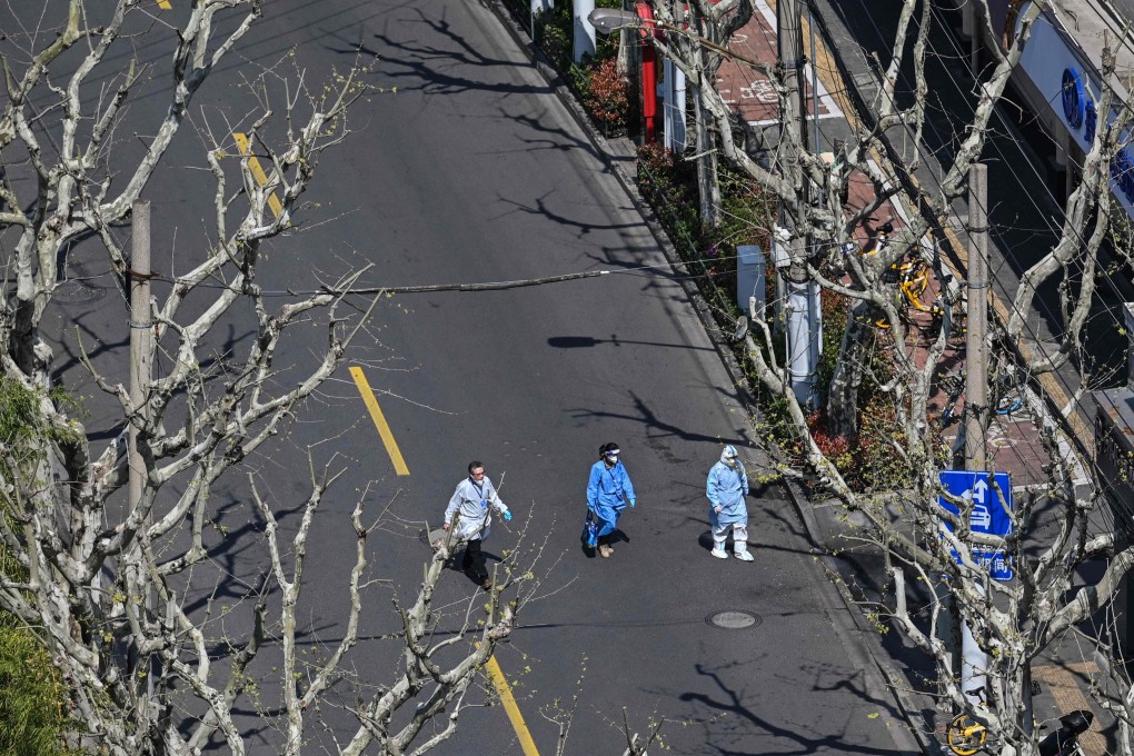 Workers wearing protective gear walk on a street during the second stage of a Covid-19 lockdown in the Jing’an district in Shanghai on April 3, 2022. Photo: AFP