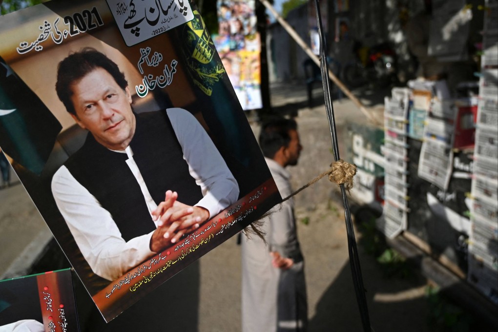 A man stands by a picture of Pakistan’s Prime Minister Imran Khan while he looks at newspapers on sale on Monday, a day after Khan foiled an attempt to boot him from office. Photo: AFP