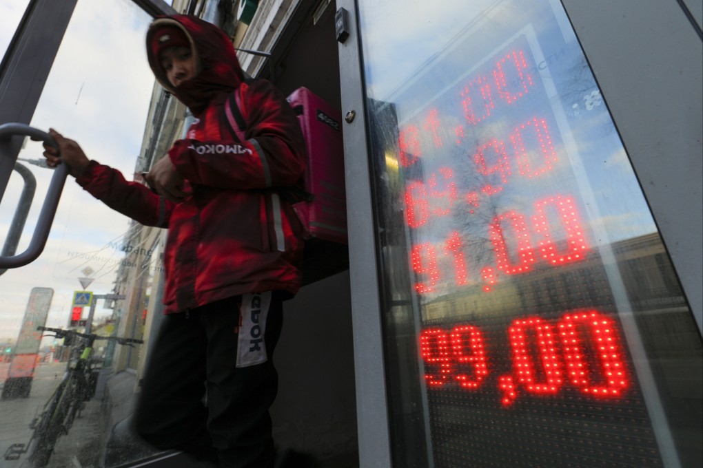 A delivery man leaves an exchange office with screen showing the currency exchange rates of US Dollar and Euro to Russian Rubles in Moscow. Photo: AP