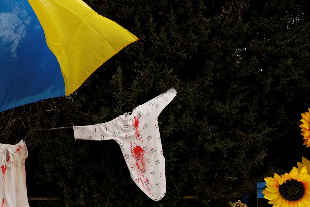 A Ukrainian flag and children’s clothes with red paint symbolising blood, outside the Russian embassy in Madrid, Spain, on Tuesday. Photo: Reuters