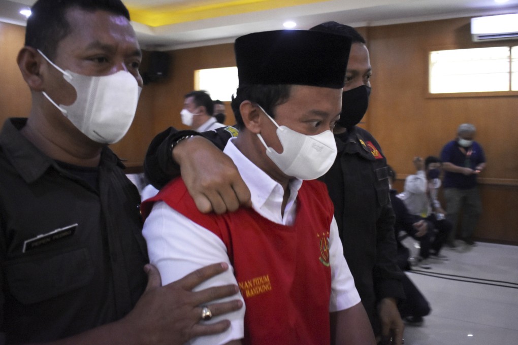 Herry Wirawan, centre, is escorted by security officers at a court in Bandung, Indonesia, for his initial sentencing hearing in February. Photo: AP