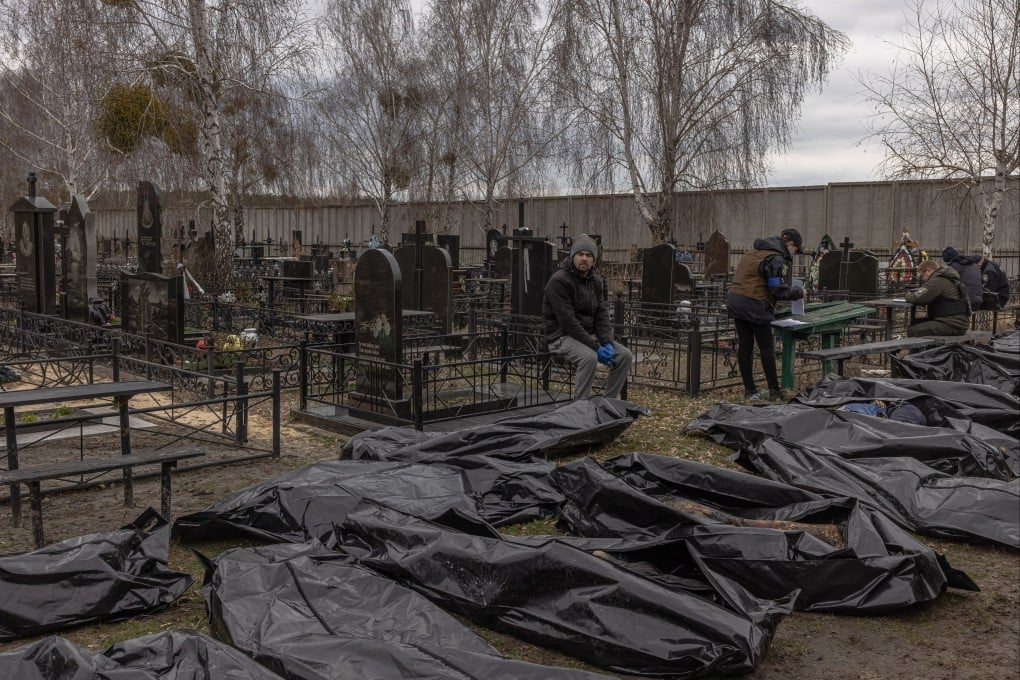 A man looks at bodies of killed people brought to a cemetery in Bucha, Ukraine, on Wednesday. Photo: EPA-EFE