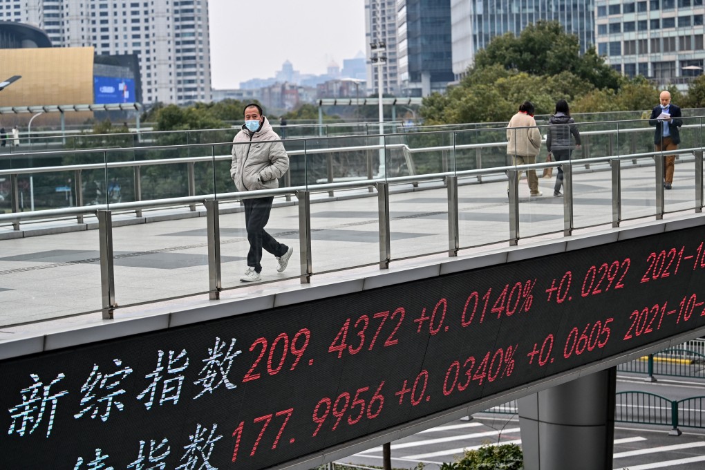 People walk across a bridge with a ticker board showing stock prices in Shanghai’s financial district. Photo: AFP