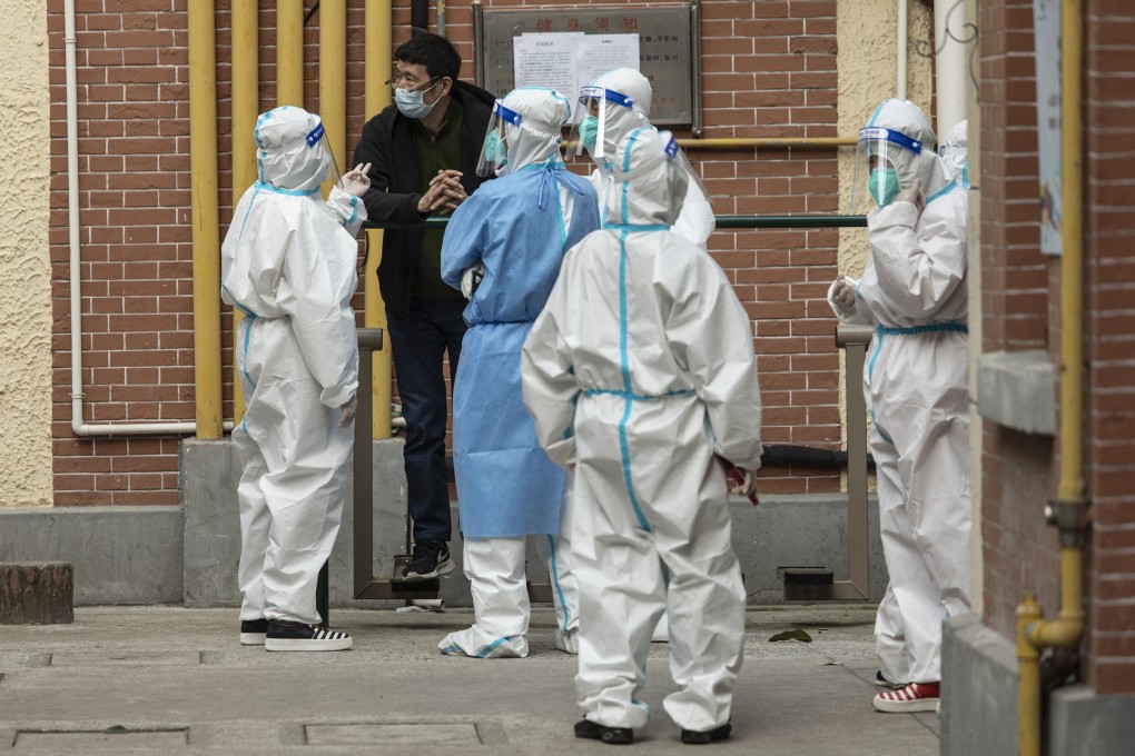 Workers in personal protective equipment (PPE) speak to a resident taking part in a round of Covid-19 testing during a lockdown in Shanghai on Thursday, April 7, 2022. Photor: Bloomberg