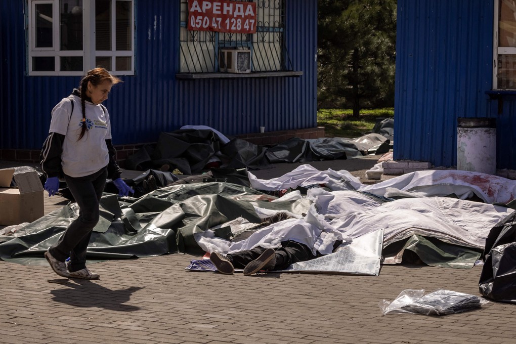 A woman passes by bodies covered with plastic sheets after a rocket attack at a train station in Kramatorsk, eastern Ukraine. Photo: AFP