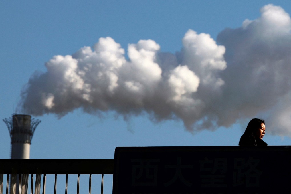 A woman walks past a chimney billowing smoke from a coal-burning power station in central Beijing. Photo: Reuters