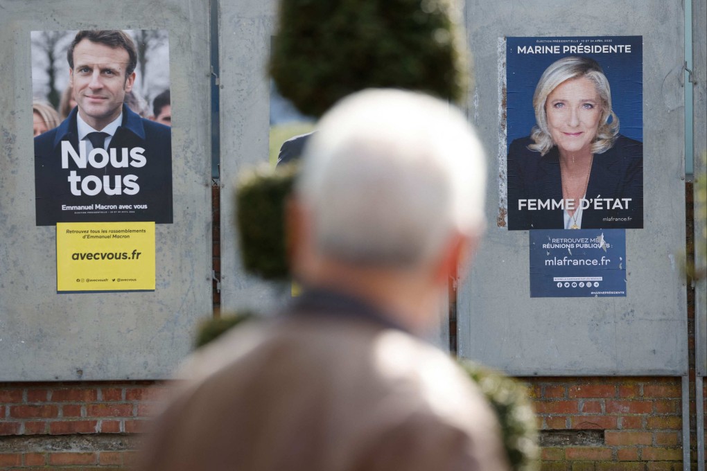 A man walks by campaign posters in Denain, France. Photo: AFP