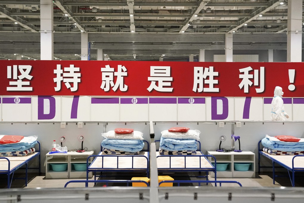 A healthcare worker walks past a banner reading “Persistence is victory!” at a makeshift hospital and quarantine facility in Shanghai on Monday. Photo: Xinhua