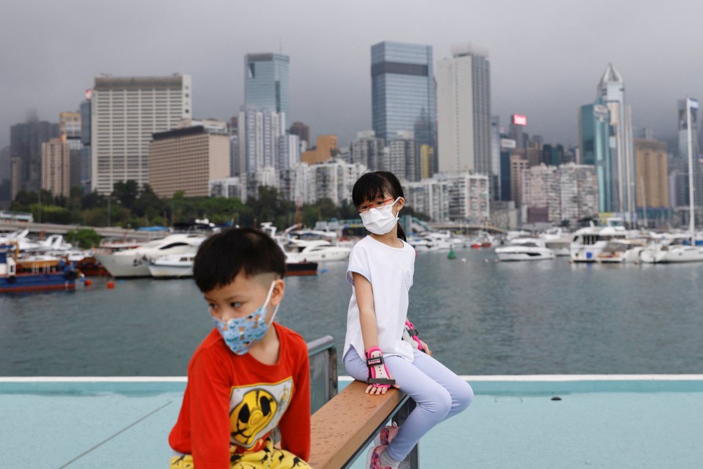 Children wearing face masks rest next to Victoria Harbour on March 25. Photo: Reuters