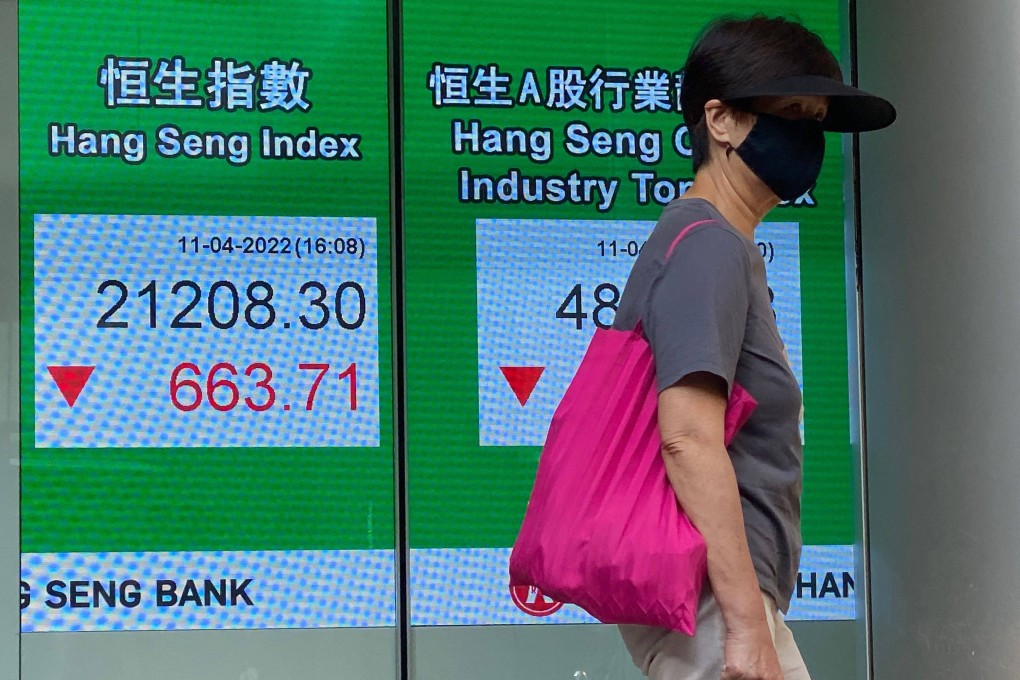 A woman walks past a sign showing the Hang Seng Index in Hong Kong on April 11. Photo AFP