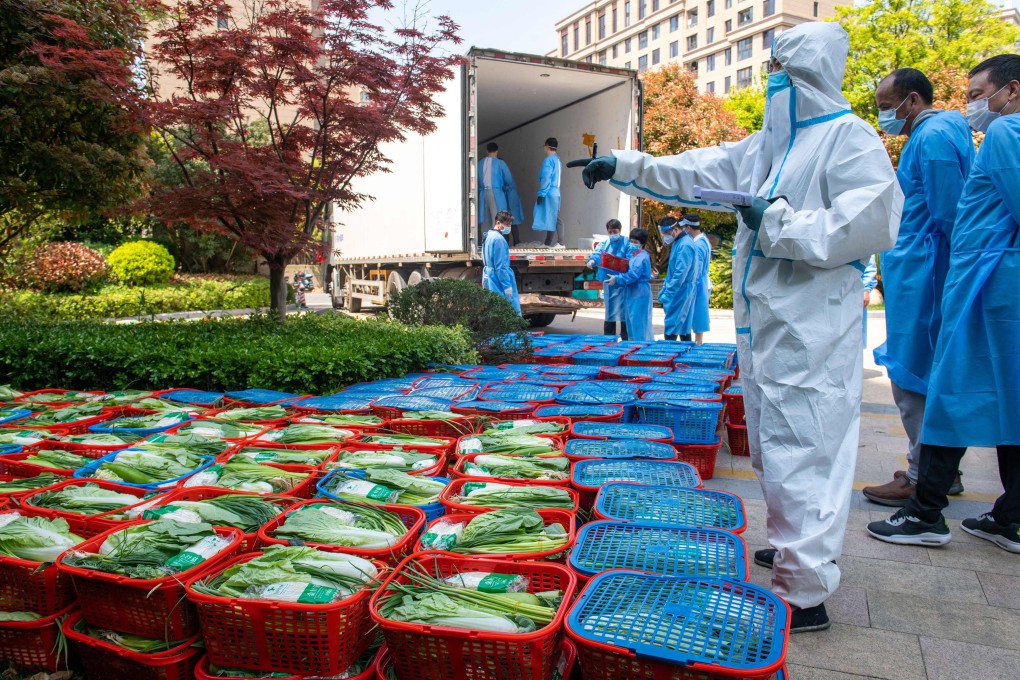 A community volunteer wearing personal protective equipment checks out vegetables to be distributed by local government to residents in a compound during a Covid-19 lockdown in Pudong district in Shanghai on April 12, 2022. Photo: AFP