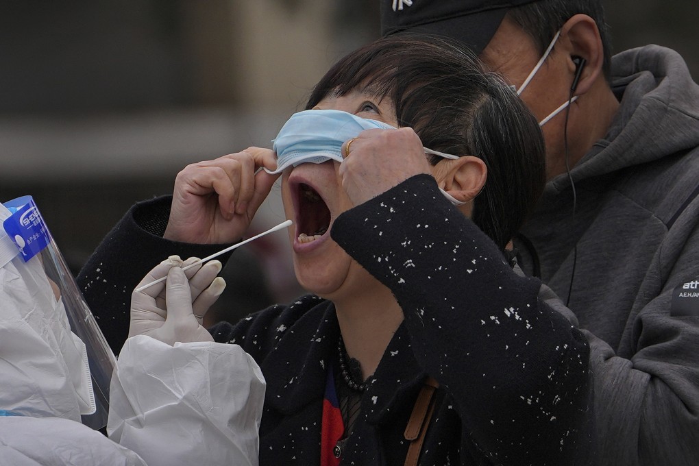 A woman pulls up her mask to get her throat swab at a coronavirus testing site in Beijing on April 6. Photo: AP