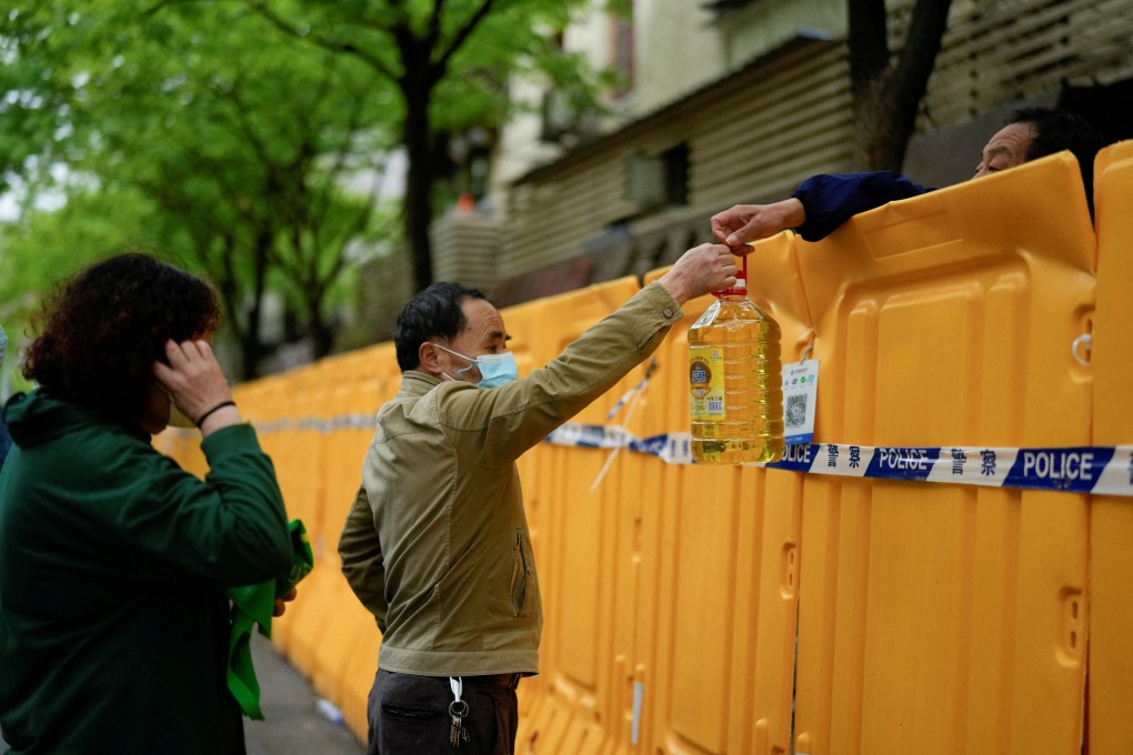 People pass edible oil over the barriers at a street market under lockdown amid the coronavirus disease (Covid-19) pandemic, in Shanghai on April 13, 2022. Photo: Reuters