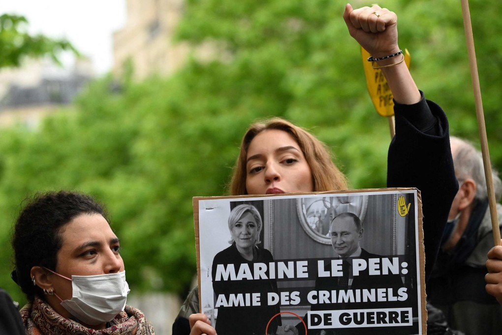 A protester in Paris holds a photo of French presidential candidate Marine Le Pen shaking hands with Russian President Vladimir Putin. The sign reads: “Marine Le Pen: friend of war criminals”. Photo: AFP