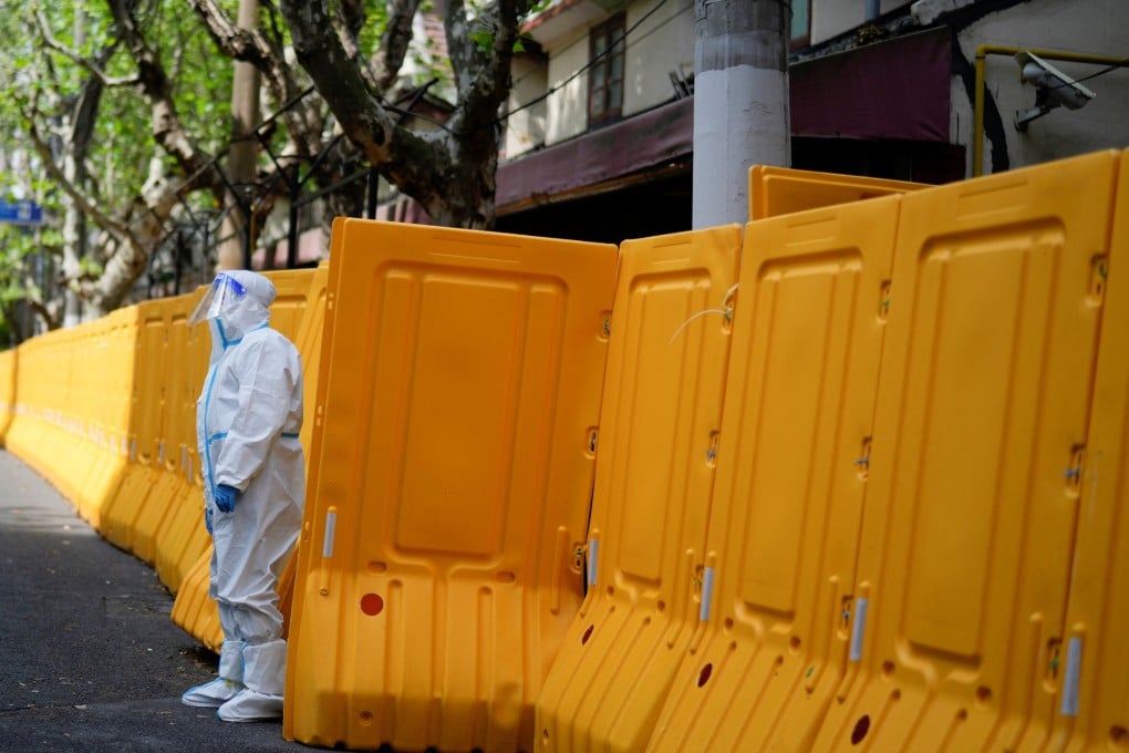A worker in a protective suit keeps watch at barriers sealing off an area under lockdown in Shanghai, China on April 15. Photo: Reuters