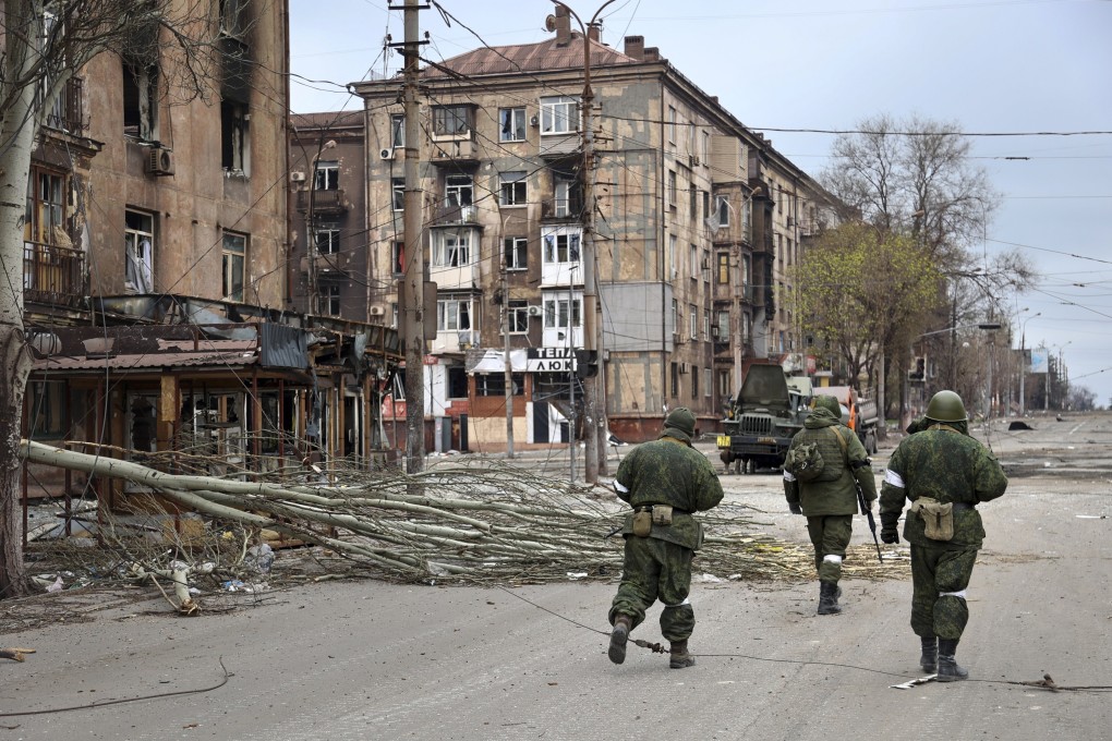 Servicemen of Donetsk People’s Republic militia walk past damaged buildings in Mariupol. Photo: AP