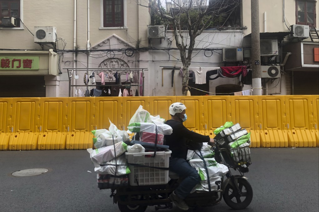 A delivery man passes by barriers set up to lock down a community in Shanghai, China, on March 30. Residents of Shanghai have struggled to buy food supplies under anti-coronavirus controls that have confined most of its 25 million people in their homes, as the government tries to contain a spreading outbreak. Photo: AP