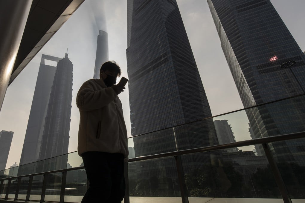 A pedestrian looks at their smartphone while walking through the Lujiazui Financial District in Shanghai on January 4. Photo: Bloomberg