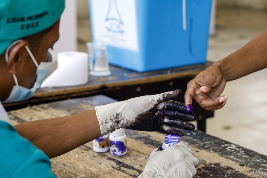 An election worker marks the finger of a voter with ink during the presidential runoff election at a polling station in Dili, East Timor on Tueday. The runoff election is between former president and Nobel Peace Prize laureate Jose Ramos Horta, and incumbent president Francisco Guterres. Photo: EPA-EFE