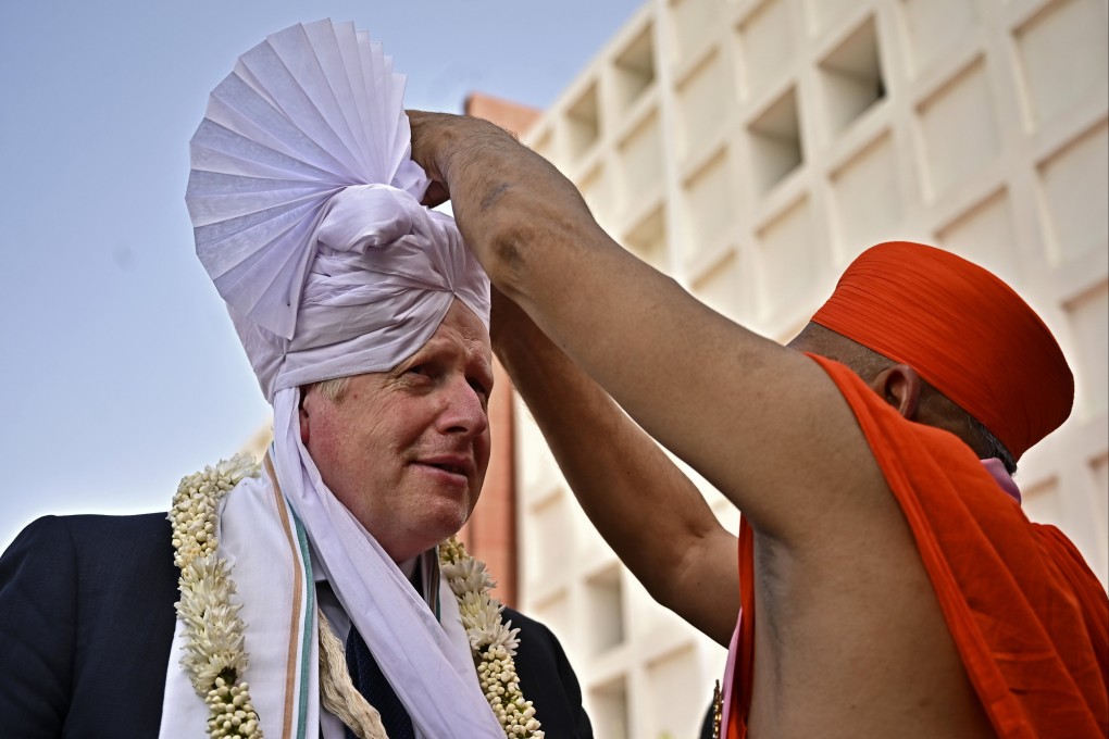 Britain’s Prime Minister Boris Johnson has a traditional turban tied on his head as he arrives to visit the Gujurat Biotechnology University, in Gandhinagar, part of his two-day trip to India. Photo: Pool via AP