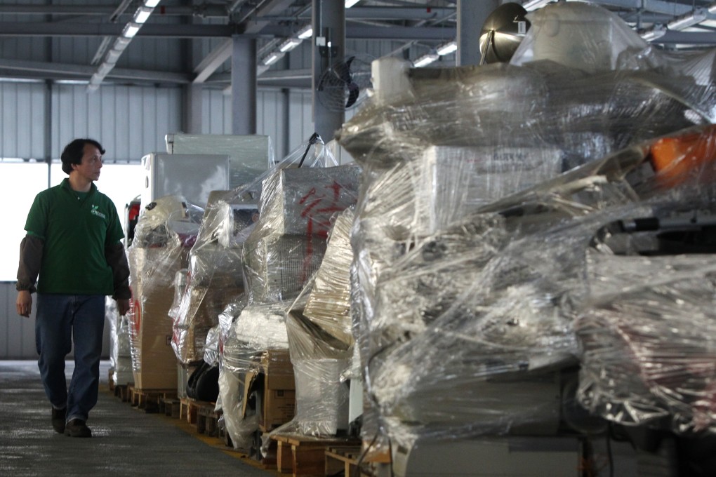 A worker of WEEE Recycling Centre walks past old electrical appliances collected at EcoPark WEEE Recycling Centre in Hong Kong’s Tuen Mun district on 27 January 2011. Photo: SCMP