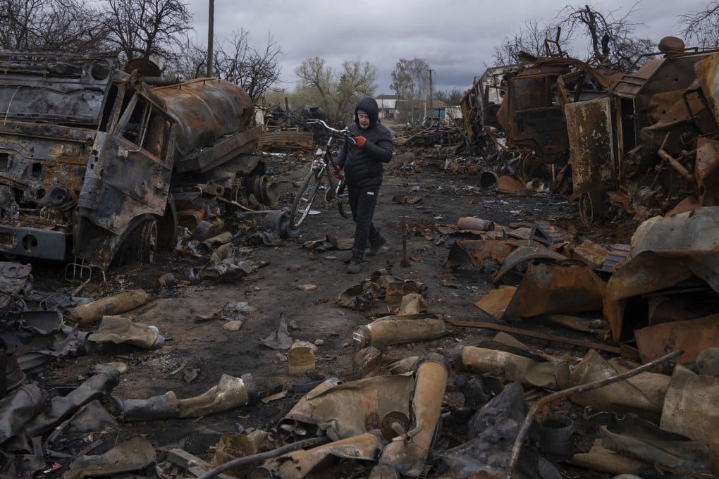 A man carries a bicycle along a street filled with destroyed Russian military vehicles near Chernihiv, Ukraine, on April 17. Photo: AP