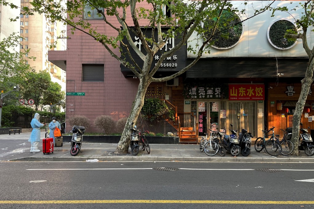 People in protective suits stand near closed stores on a street amid the coronavirus outbreak in Shanghai, China April 21. Photo: Reuters