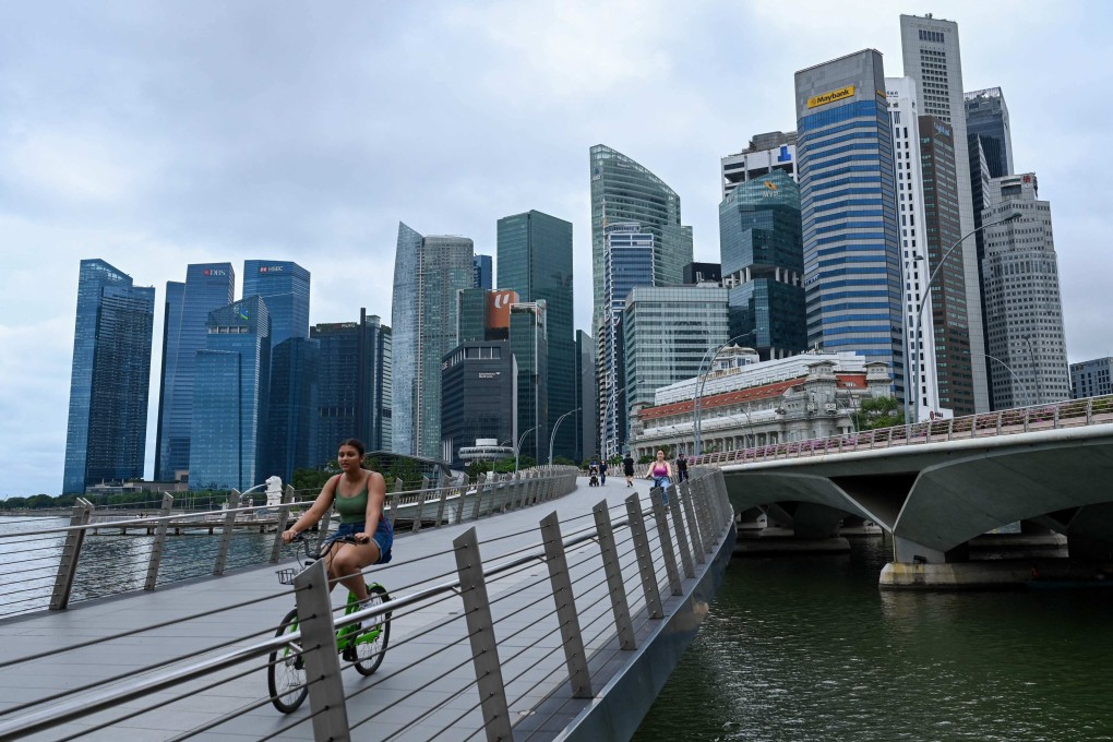 People ride bikes across a bridge next to the financial business district in Singapore. Photo: AFP