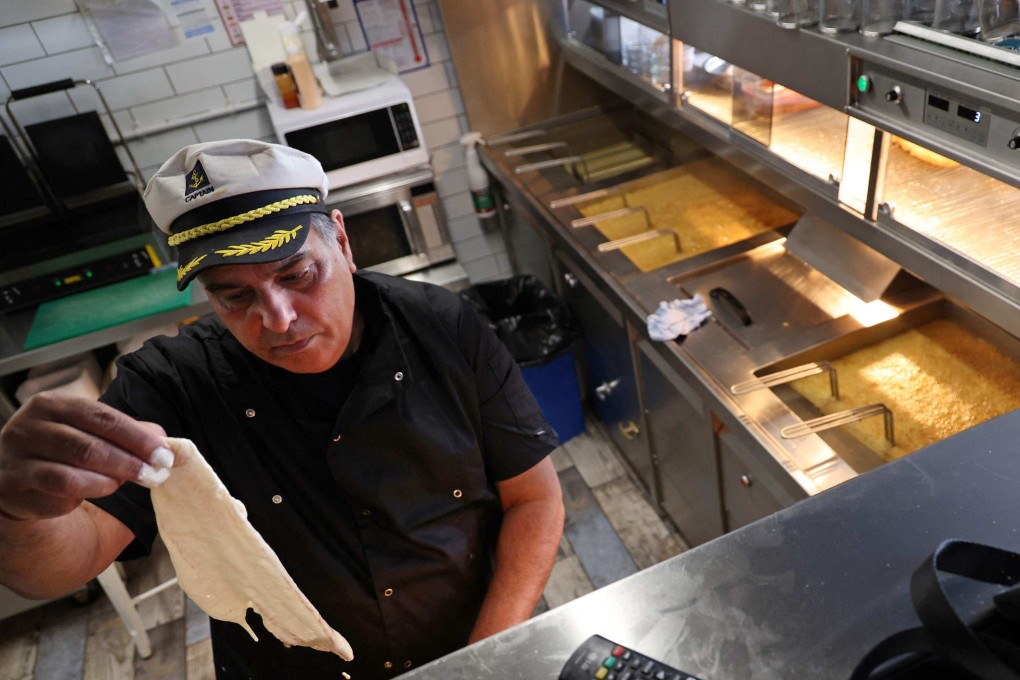 A shop owner batters fish for frying in Brighton on March 25. Britain’s fish and chip shops are running low on white fish after cutting off supplies from Russia. Photo: AFP
