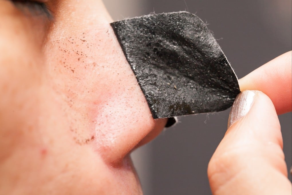 A woman uses a clear-up strip to remove blackheads from around her nose. Up to 20 per cent of adults have blackheads, say experts, the result of clogged pores. Photo: Shutterstock