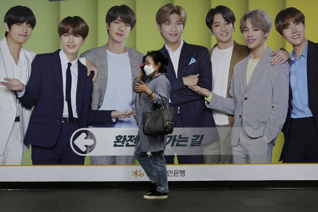 A woman walks past a board showing members of BTS in Seoul. File photo: AP