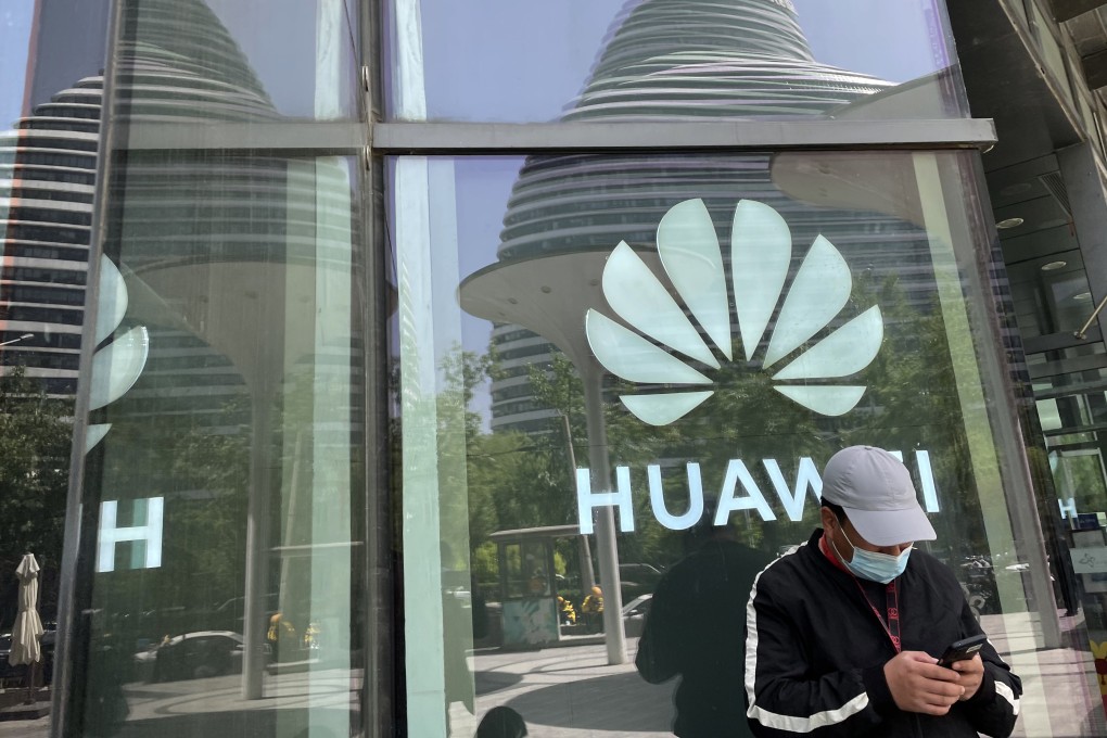 A man uses his smartphone in front of a Huawei logo in Beijing, April 27,  2022. Photo: SCMP/Simon Song