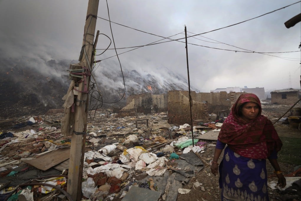 A ragpicker living on the edge of Bhalswa landfill in New Delhi walks past as it burns on Wednesday amid an extreme heatwave sweeping India. Photo: AP