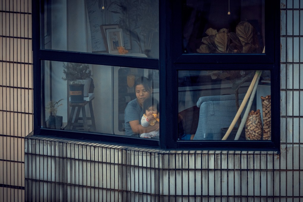 A woman and a baby in quarantine look through the window of their apartment amid Covid-19 full lockdown  in Shanghai, China, on April 27. Photo: EPA-EFE