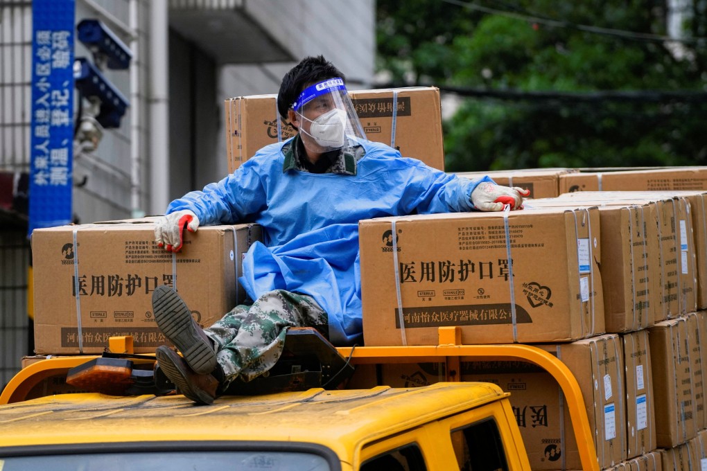 A worker in a protective suit sits on top of a truck, as he transports masks during a lockdown in Shanghai, April 28, 2022. Photo: Reuters