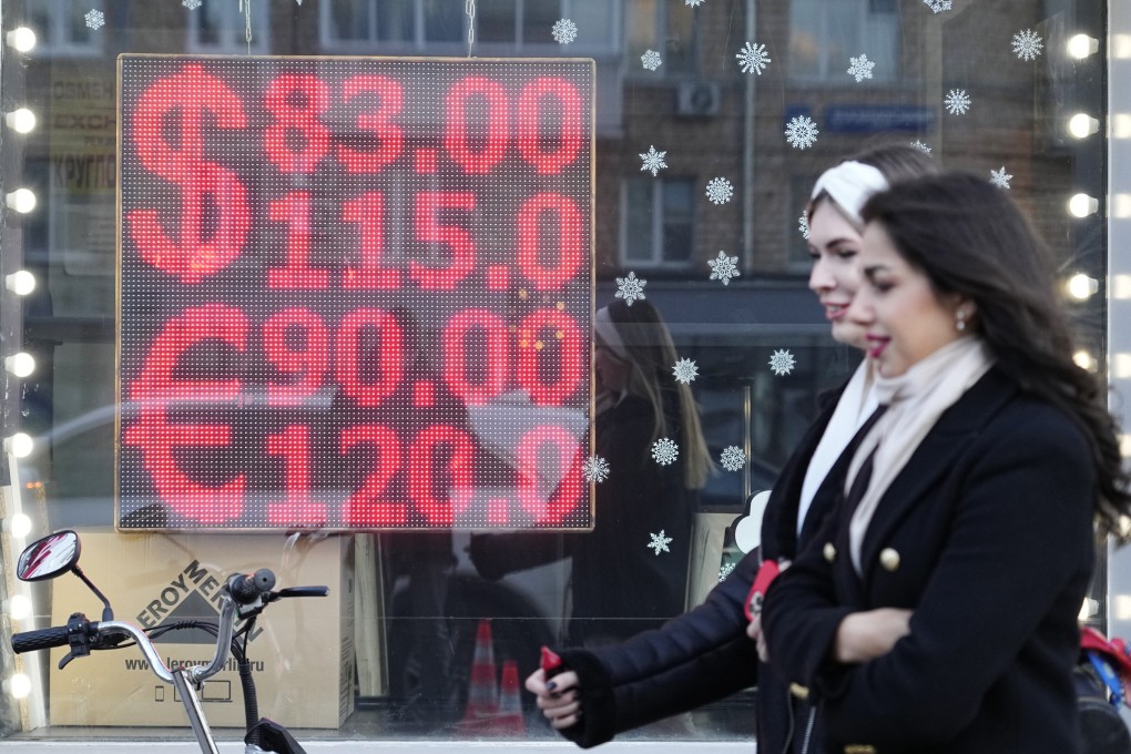 People walk past a currency exchange office screen displaying the exchange rates of American dollars and the Euro to Russian Rubles in Moscow’s downtown. Photo: AP