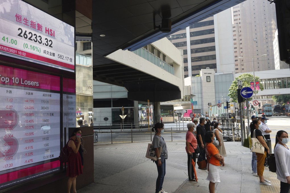 People stand in front of a bank’s electronic board showing the Hong Kong Stock Exchange index. Photo: AP