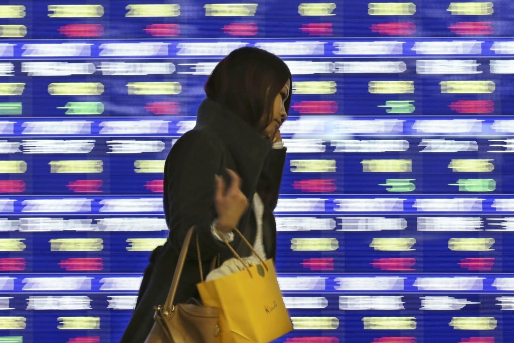 A woman walks past an electronic stock board in Tokyo. Even though much airtime has been given to criticising gender inequality at work, change has been slow. Photo: AP