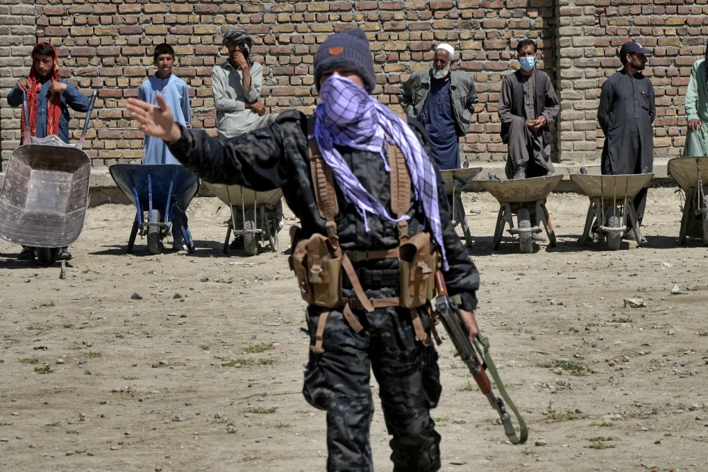 A Taliban fighter stands guard as people wait to receive food rations distributed by a Chinese humanitarian aid group, during the holy month of Ramadan, in Kabul, Afghanistan on Saturday. Photo: AP