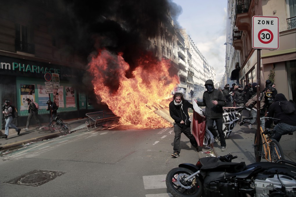 Protesters walk with a banner next to rubbish and materials that were set alight during a May Day demonstration march from Republique, Bastille to Nation in Paris, France on May 1. Photo: AP