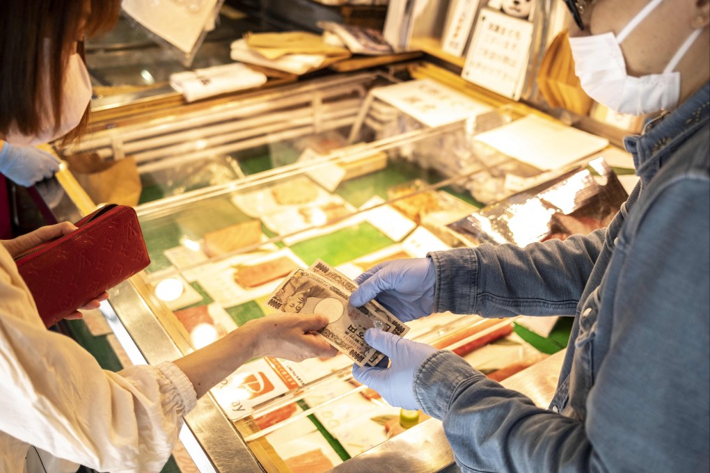 A woman pays for goods with yen banknotes at a shop in Tokyo. Most Japanese expect goods to become more expensive this year, a government survey found. Photo: AFP